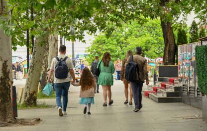 Otac vodi kćerku za ruku dok hodaju ulicom. Muškarci i žene šetaju gradom. Ljudi na ulici.