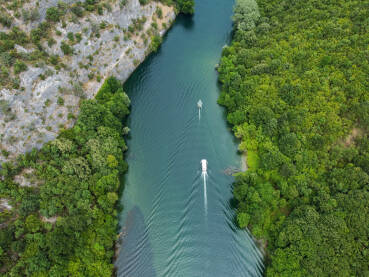 Duboki kanjon rijeke između planina, snimak dronom. Kanjon Matka, Sjeverna Makedonija. Turistički brodić plovi rijekom.