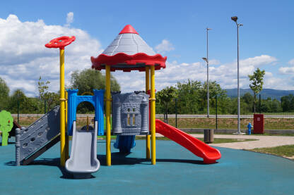 Šareni plastični tobogani u dječijem parku na plavoj podlozi.