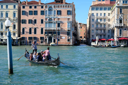 Turisti u Veneciji Venecija, Italija: Historijske građevine duž riječnog kanala. Popularno turističko odredište. Gondola sa turistima na vodi.