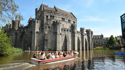 Gent, Belgija: Dvorac uz rijeku. Turisti Gent, Belgija: Dvorac uz rijeku u centru grada. Turisti na čamcima na rijeci.