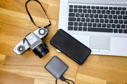 CAM14249 Laptop, telefon i fotoaparat na pozadini drvenog stola - koncept putovanje