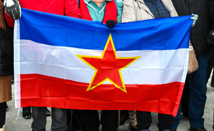 Ljudi sa zastavom bivše Jugoslavije. SFRJ Ljudi sa zastavom bivše Jugoslavije. Socijalistička Federativna Republike Jugoslavije, SFRJ. Ljudi drže zastavu u rukama.