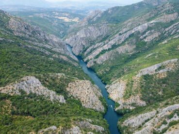 Duboki kanjon rijeke između planina, snimak dronom.  Kanjon Matka, Sjeverna Makedonija. Turistički brodić plovi rijekom.