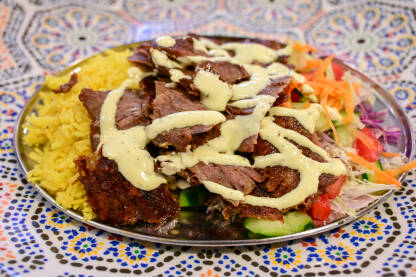 Ukusan kebab serviran sa povrćem i rižom u restoranu. Ukusan kebab serviran sa povrćem i rižom u restoranu. Tradicionalno jelo na tanjiru.