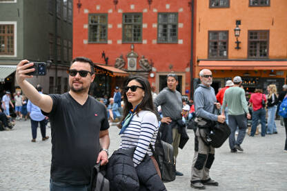 Stockholm, Švedska: Par pravi selfi na trgu ispred poznate znamenitosti. Turisti prave selfie na historijskom trgu. Sretan par se fotografira.