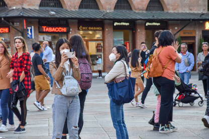 Turisti u Italiji Grupa turista na ulici u Italiji. Ljudi šetaju i fotografišu ulice Bolonje. Žene na ulici.