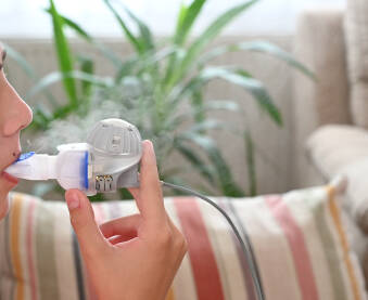 Dječak koristi inhalator zbog respiratornih problema. Mladi pacijent udiše lijekove inhalatorom. Dječak s astmom koristi inhalator.