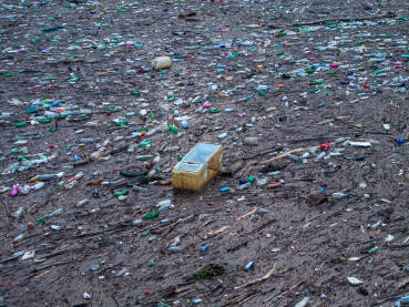 Razni oblici komunalnog otpada nagomilani u rijeci Drini, vidljivi na površini i uz obalu.