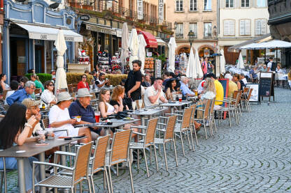 Turisti piju piće u kafiću Strazbur, Francuska: Ljudi sjede i piju piće u kafiću. Turisti na ručku u restoranu.