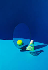 Loptica za badminton Loptica za badminton s refleksijom teniske loptice u ogledalu na plavoj pozadini.