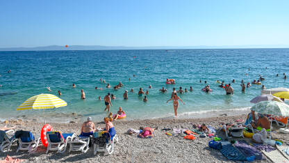 Ljudi se kupaju i sunčaju Turisti na moru. Ljudi se kupaju i sunčaju u Jadranskom moru. Ljetni odmor. Grupa turista na plaži tokom toplog ljetnog dana. Makarska, Hrvatska.