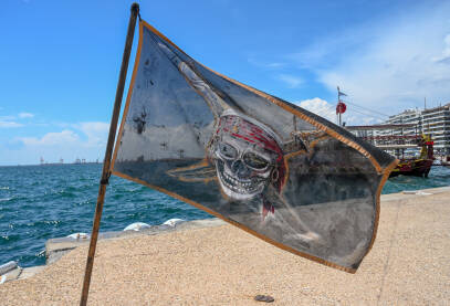 Piratska zastava na moru. Zastava sa likom gusara s mora u pozadini. Lubanja na crnoj gusarskoj zastavi.