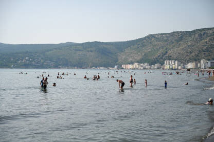 Shëngjin, Albanija, Popularna turistička destinacija. Shëngjin, Albanija. Ljudi plivaju u moru i sunčaju se na plaži. Turisti na ljetnom godišnjem odmori. Popularna turistička destinacija na Jadranskom moru u Albaniji.