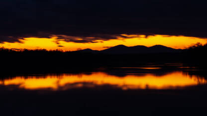 Planina Motacija u sumrak Simetrična refleksija siluete planine Motajice u rijeci Savi okružena tamnim oblacima u sumrak u dugoj ekspoziciji