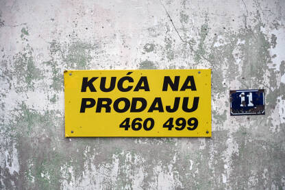 "Kuća na prodaju", natpis na tabli. "Kuća na prodaju", natpis na tabli. Prodaja nekretnina. Prodaje se kuća sa starom i trošnom fasadom.
