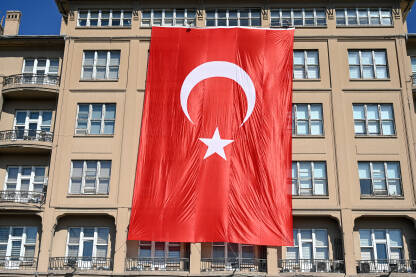 Turska zastava na zgradi. Ogromna turska zastava na zgradi. Nacionalna zastava Turske. Državni i nacionalni simbol. Crvena zastava s bijelom zvijezdom i polumjesecom. Turska.