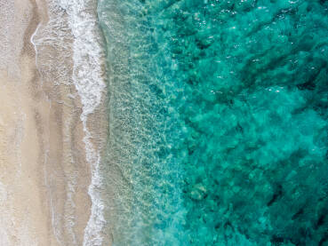 Pješčana plaža i more, snimak dronom. Pješčana plaža i more, snimak dronom. Prekrasna tropska plaža tokom ljeta. Snimak dronom na valove koji se razbijaju na plaži s pijeskom. Prozirna morska voda.