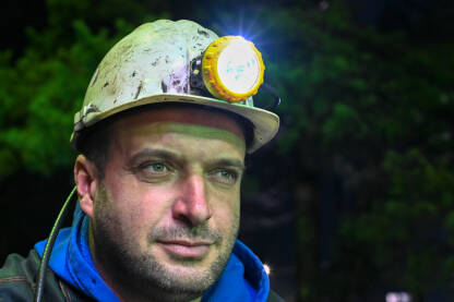 Rudar Portret rudara u rudniku. Rudar u radnom odijelu i s kacigom i svjetiljkom na poslu.