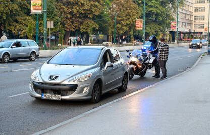 Saobraćajni policajac zaustavlja vozila i provjerava dokumente. Policajac na motociklu zaustavio vozača. Saobraćajni policajac provjerava dokumente vozača. Policajac na poslu.
