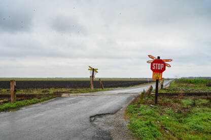 Željeznički prelaz sa znakom stop. Prelaz preko pruge u ravnici.