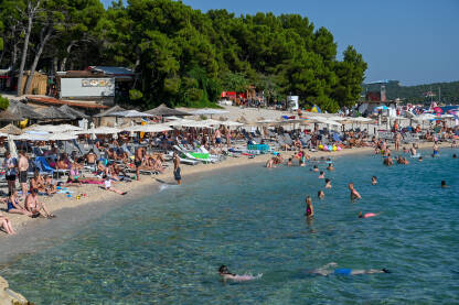 Plaža u Makarskoj puna ljudi Turisti na moru. Ljudi se kupaju i sunčaju u Jadranskom moru. Ljetni odmor. Grupa turista na plaži tokom toplog ljetnog dana. Makarska, Hrvatska.