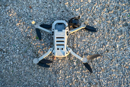 Srušen i oštećen dron na asfaltu. Srušen i oštećen dron na asfaltu. Slomljeno kućište i kamera drona. Dron pao na zemlju. Nesreća tokom leta.