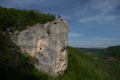 Penjač na prirodnoj stijeni. Muškarac se penje uz stijenu. Stijena za penjanje u selu Pecka.