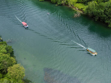 Duboki kanjon rijeke između planina, snimak dronom. Kanjon Matka, Sjeverna Makedonija. Turistički brodić plovi rijekom.