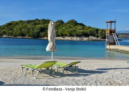 Ležaljke i suncobran na praznoj plaži tokom lijepog sunčanog dana.