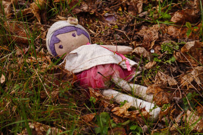 Odbačena prljava krpena lutka u travi.