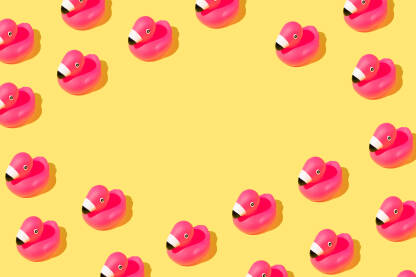 Ljetna pozadina s ružičastim gumenim flamingo pticama na žutoj pozadini.