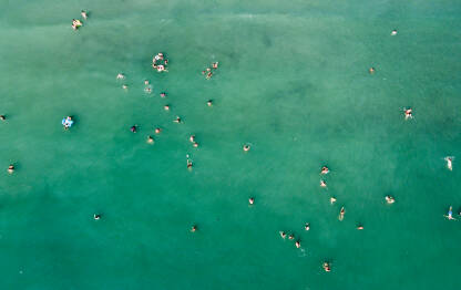 Turisti plivaju u moru. Grupa ljudi se zabavlja u vodi tokom ljetnog odmora. Ljudi uživaju u moru.