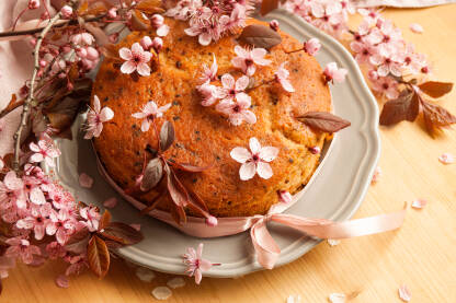 Torta ukrašena proljetnim rozim cvijetovima trešnje na stolu.