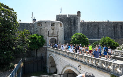 Dubrovnik, Hrvatska: Grupa turista u starom gradu. Stare zidine. Dubrovnik, Hrvatska: Grupa turista u starom gradu. Ljudi hodaju preko mosta. Stare zidine i zgrade u Dubrovniku. Popularno turističko odredište na Jadranskom moru.