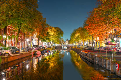Kanal u Amsterdamu Zgrade, drveće i kanal u Amsterdamu noću. Grad Amsterdam, Holandija. Holandske kuće.