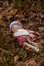 Odbačena prljava krpena lutka u travi.