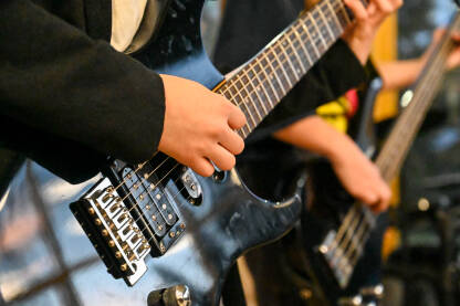 Mladi gitaristi sviraju električnu gitaru i bas gitaru na koncertu. Mladi gitaristi sviraju električnu gitaru i bas gitaru na rock koncertu. Muzičar svira gitaru sa bendom na bini na muzičkom festivalu.
