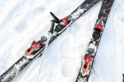 Skije i skijaški štapovi u snijegu Skije i skijaški štapovi u snijegu na planini. Zimski sport i rekreacija. Skijanje.