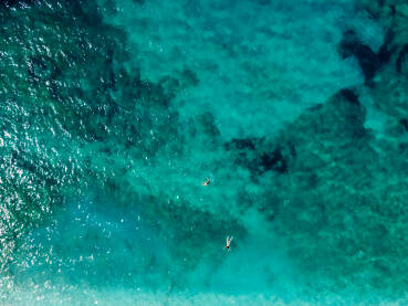 Plivači u moru, snimak dronom. Turisti rone i plivaju u vodi, snimak iznad. Prozirna morska voda u zaljevu. Ljetni odmor.