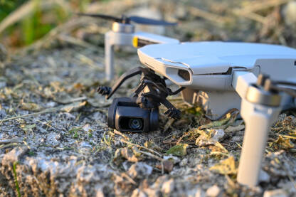 Srušen i oštećen dron. Srušen i oštećen dron. Slomljena kamera drona na asfaltnom putu. Dron pao na zemlju. Nesreća tokom leta.