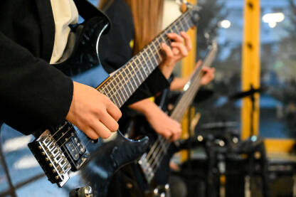 Mladi gitaristi sviraju električnu gitaru i bas gitaru na koncertu. Mladi gitaristi sviraju električnu gitaru i bas gitaru na rock koncertu. Muzičar svira gitaru sa bendom na bini na muzičkom festivalu.