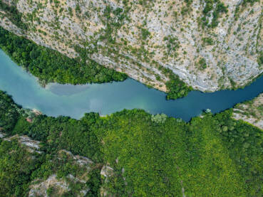 Duboki kanjon rijeke između planina, snimak dronom.  Kanjon Matka, Sjeverna Makedonija. Turistički brodić plovi rijekom.