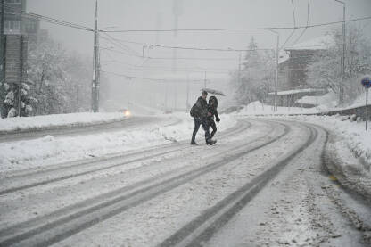 Ljudi prelaze ulicu pokrivenu snijegom. Ljudi prelaze ulicu pokrivenu snijegom.