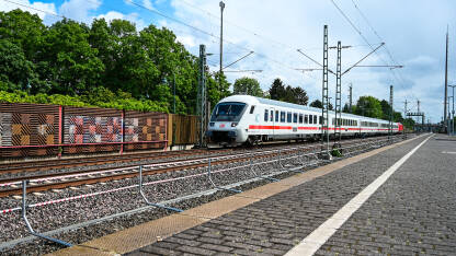 Putnički voz prolazi kroz željezničku stanicu Putnički voz prolazi kroz željezničku stanicu. Željeznički prijevoz. Moderni vlak u Njemačkoj.
