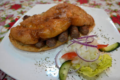 Ćevapi ili ćevapčići. Tradicionalno mesno jelo na Balkanu. Ćevapi ili ćevapčići. Tradicionalno mesno jelo na Balkanu. Meso pripremljeno na roštilju i servirano uz somun i luk. Popularna hrana.