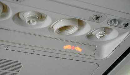 Upaljena lampica za vezivanje pojasa u avionu. Upozorenje putnicima da vežu sigurnosni pojas tokom leta.