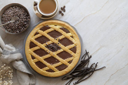 Mramorni stol sa serviranom čokoladnom pitom, vanilijom i bijelom kafom.