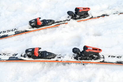 Skije i skijaški štapovi u snijegu Skije i skijaški štapovi u snijegu na planini. Zimski sport i rekreacija. Skijanje.