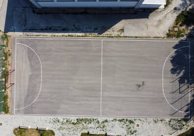 Igralište za mali fudbal ispred škole. Asfaltirani fudbalski stadion, snimak dronom. Igralište za mali fudbal ispred škole.